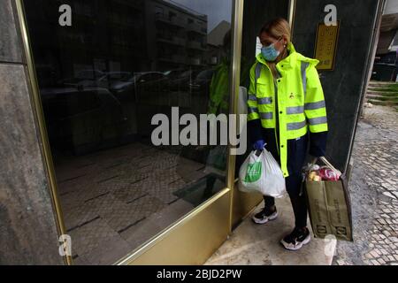 Lisbonne, Portugal. 27 avril 2020. Un volontaire portant un masque de protection et des gants livre des sacs de nourriture et des produits hygiéniques à différents endroits de la ville. Le Conseil communal de Penha de França a réalisé un projet appelé 'magasin d'alimentation sociale', lorsqu'une structure est utilisée pour stocker des produits alimentaires et d'hygiène personnelle donnés par les supermarchés et les écoles. Ces derniers sont emballés et ensuite distribués par des travailleurs bénévoles à des personnes, en particulier les personnes âgées et les malades, qui sont sans abri ou physiquement incapables, et qui sont dans une situation vulnérable en raison de la séquestration obligatoire à cause DE COVI Banque D'Images