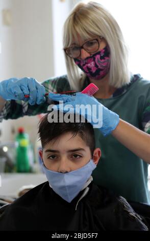 Belgrade, Serbie. 29 avril 2020. Un coiffeur, portant un masque de protection et des gants de protection, coupe les cheveux du client qui porte également un masque de protection. Les autorités serbes ont décidé d'assouplir certaines des mesures restrictives permettant à certaines entreprises de rouvrir leurs magasins dans le but d'assouplir certaines des mesures qui ont été mises en place pour limiter la propagation du coronavirus SRAS-COV-2, qui cause la maladie COVID-19. Crédit: Koca Sulejmanovic/Alay Live News Banque D'Images