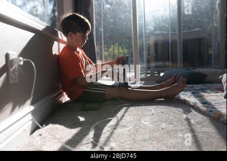 Profil de garçon utilisant ipad tablette sur le sol de sa maison Banque D'Images