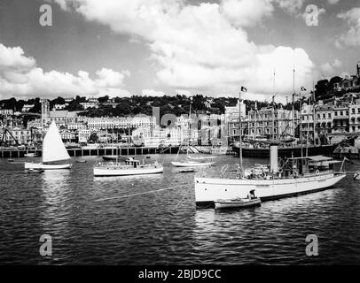 Photo noir et blanc vintage du début du XXe siècle montrant le port de Torquay sur la côte sud de l'Angleterre. La photo montre divers bateaux et bateaux dans le port. L'hôtel White House, l'hôtel Norfolk, l'hôtel St. James et l'hôtel Regina sont également visibles. Banque D'Images