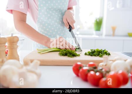 Vue rapprochée de sa fille des mains, qui fait le repas, coupe de la salade verte de perte de poids en vitamine sur le bureau de table de coupe en bois blanc moderne Banque D'Images