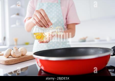 Photo courte de la belle femme de ménage tenir l'huile d'olive verser poêle chaude profiter de la cuisine de matin hobby repas savoureux table familiale stand lumineux cuisine Banque D'Images