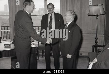Dans les années 60, dans un élégant bureau lambrissé de bois de la ville de Londres, une entreprise gérant le directeur agité la main et félicitant un employé de longue date pour son travail, Londres, Angleterre, Royaume-Uni. Banque D'Images
