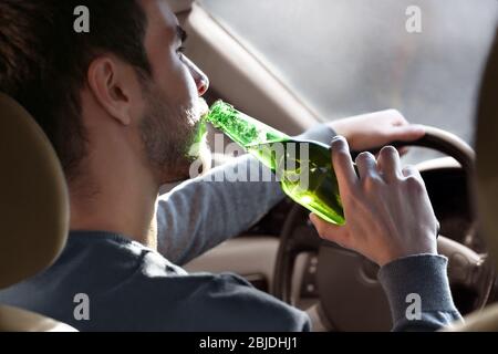 Homme buvant de la bière en voiture, à proximité. Ne buvez pas et ne conduisez pas Banque D'Images