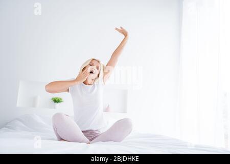 Portrait d'elle belle jolie jolie jolie jolie femme dorlotée séniée dans un lit s'évertant en blanc clair moderne Banque D'Images