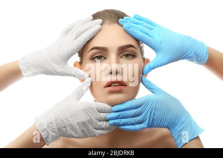 Les mains touchent le visage de la femme sur fond blanc. Concept de chirurgie plastique Banque D'Images