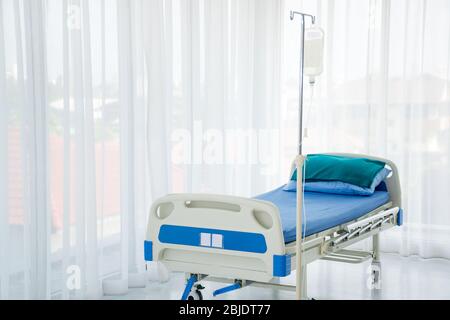 Lit d'hôpital vide pour un patient malade avec un sac de liquide et un poteau dans une chambre ou un service de patient ou une salle d'examen à l'hôpital Banque D'Images