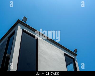 Bâtiment moderne en béton avec fenêtres en verre et projecteur LED sur fond bleu ciel avec espace de copie. Banque D'Images