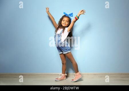 Jolie petite fille africaine américaine en denim contre le mur bleu. Concept de mode Banque D'Images