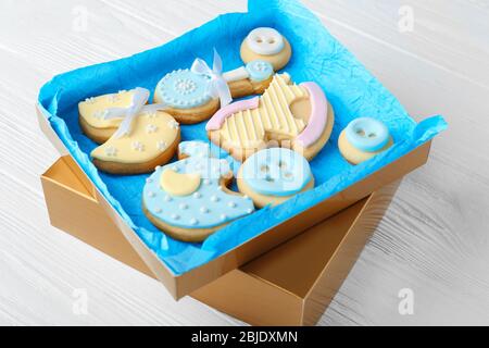 Petits cookies décorés de glaçure dans une boîte, sur fond en bois Banque D'Images