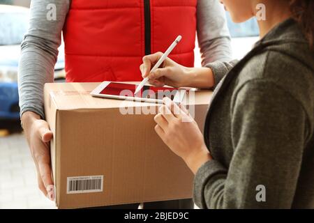 Jeune femme qui ajoute la signature après avoir reçu le colis du courrier, clôture Banque D'Images