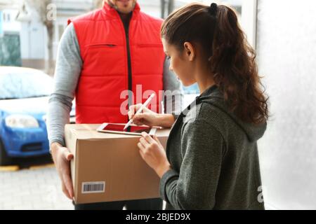 Jeune femme qui ajoute la signature après avoir reçu le colis du courrier Banque D'Images