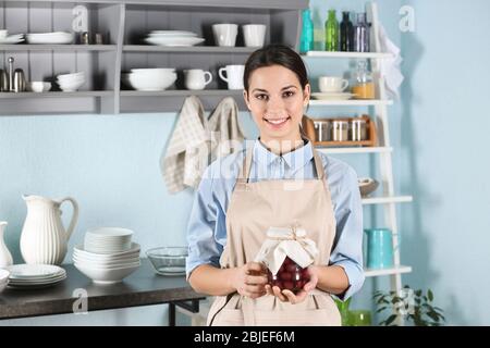 Femme dans un tablier tenant le pot avec de la confiture sur la cuisine ancienne Banque D'Images