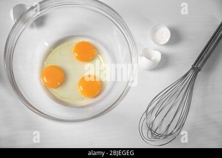 Œufs craqués dans un bol en verre sur la table de cuisine Banque D'Images