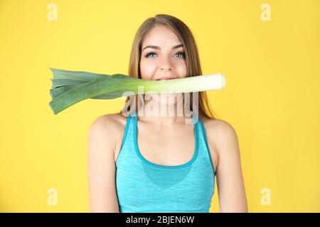 Jeune femme belle avec poireau dans la bouche sur fond jaune Banque D'Images