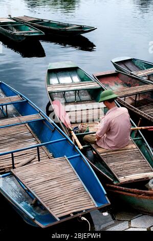 Homme de mer sur un bateau à ramer attendant les touristes en Asie du Vietnam. Banque D'Images