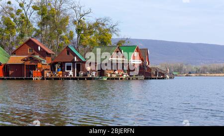 Tata, Hongrie - 03 30 2019: Les pêcheurs pêchent au lac Derito à partir de petites maisons en bois colorées sur une île. Les gens viennent ici pour se détendre. Banque D'Images