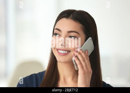 Belle jeune femme parlant par téléphone mobile à l'intérieur Banque D'Images