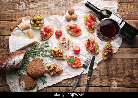 Savoureuse bruschetta servie avec du vin sur fond de bois Banque D'Images