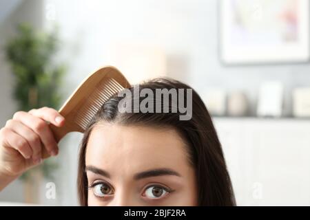 Jeune femme peignant les cheveux à la maison, la proximité Banque D'Images