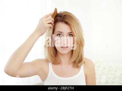 Belle jeune femme se brossant les cheveux à la maison Banque D'Images