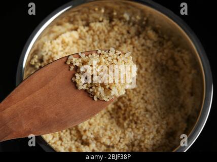 Grains de quinoa blanc biologique bouillis sur cuillère en bois, bougeée Banque D'Images