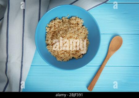 Vue de dessus de la plaque bleue avec des grains de quinoa blanc et biologique détourné sur fond de bois Banque D'Images