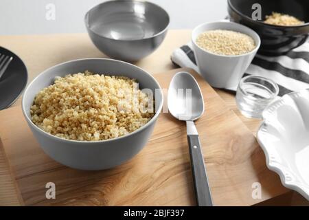 Bol en céramique avec grains de quinoa blanc et biologique bouillis sur table en bois de cuisine Banque D'Images