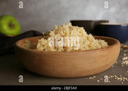 Bol en bois avec grains de quinoa blanc et biologique bouillis sur table de cuisine Banque D'Images