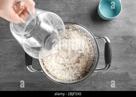 Concept de cuisson. Verser de l'eau dans une casserole avec du riz Banque D'Images