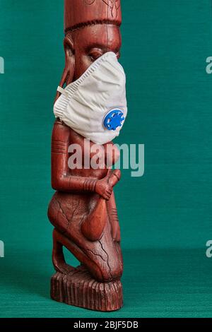 Figurine en bois sculpté comme souvenir pour les touristes voyageant en Tanzanie. Une femme de la tribu Masai porte un masque respiratoire N 95. Banque D'Images