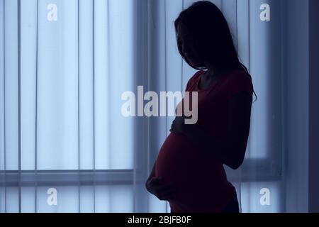 Belle femme enceinte, debout près de fenêtre à la maison Banque D'Images