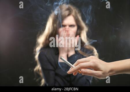 Femme couvrant le visage de la fumée de cigarette. Concept de tabagisme passif Banque D'Images
