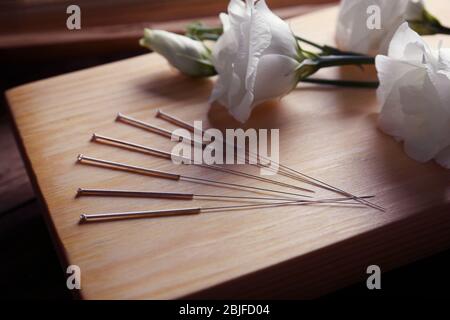 Aiguilles d'acupuncture avec fleurs sur planche en bois Banque D'Images