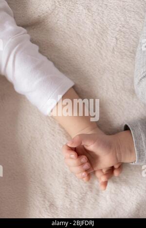 Enfance, sommeil, détente, famille, style de vie concept - deux jeunes enfants de 2 et 3 ans vêtus de body blanc et beige dorment sur un beige Banque D'Images