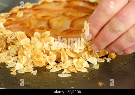 Chef main caramélisé amandes poire tarte cuisine française Banque D'Images