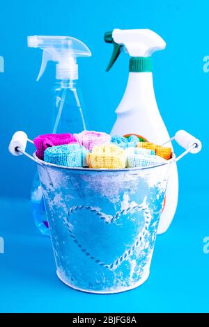 Serviettes colorées, seau et produits de nettoyage sur un fond bleu. Détergent pour différentes surfaces dans la cuisine, la salle de bains et d'autres pièces. Gros plan Banque D'Images