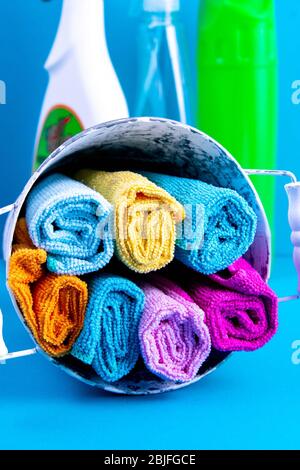 Serviettes colorées, seau et produits de nettoyage sur un fond bleu. Détergent pour différentes surfaces dans la cuisine, la salle de bains et d'autres pièces. Gros plan Banque D'Images