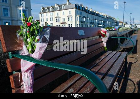 Llandudno, Royaume-Uni : 6 mai 2019 : fleurs liées à un banc sur la promenade de la rive nord de Llandudno. Le banc est en mémoire de Brian Higgot. Banque D'Images