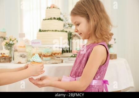 Jolie fille donnant un délicieux cupcake à son ami à la fête Banque D'Images