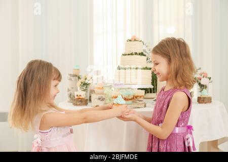 Jolie fille donnant un délicieux cupcake à son ami à la fête Banque D'Images