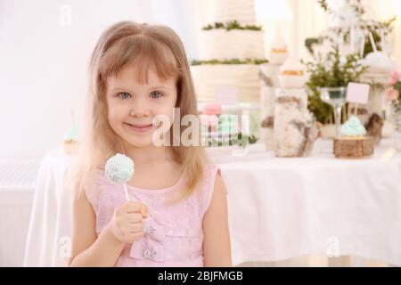 Jolie petite fille avec une délicieuse tarte pop à la fête Banque D'Images