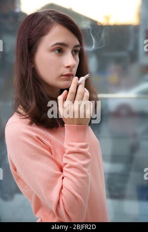 Une adolescente qui fume sur fond de fenêtre Banque D'Images