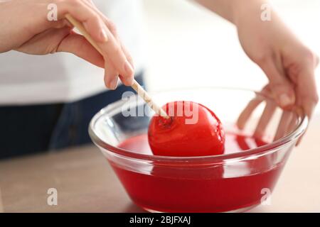 Femme qui trempait la pomme de bonbons dans un bol en verre au caramel Banque D'Images