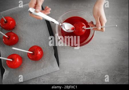 Femme vitrage de la pomme de bonbons avec caramel au-dessus de la cuvette de verre dans la cuisine Banque D'Images