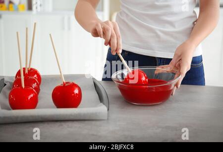 Femme qui trempait la pomme de bonbons dans un bol en verre au caramel Banque D'Images