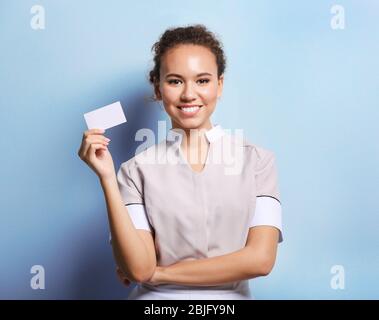 Jeune femme de chambre africaine américaine avec carte de visite sur fond clair Banque D'Images