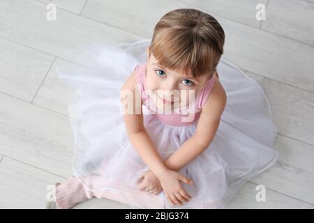 Joli petit ballerina assis sur le sol dans un studio de danse Banque D'Images