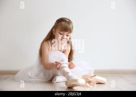 Belle danseuse de danse de petit ballet nouant des chaussures pointe dans un studio de danse légère Banque D'Images