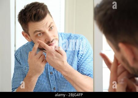 Jeune homme mettant des lentilles de contact devant le miroir à la maison Banque D'Images